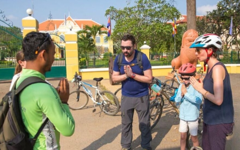 A group of tourists practicing the sampeah greeting with the tour guide in Cambodia