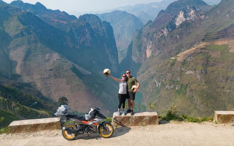 Motorbike travelers taking a photo at a panoramic viewpoint on the Ha Giang Loop, northern Vietnam