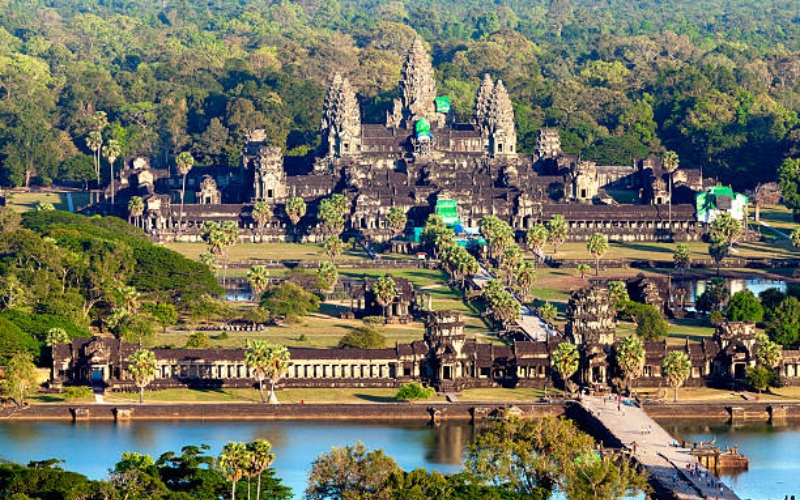 Aerial photograph of Angkor Wat in Cambodia, showing its towering spires, surrounding moat, and lush green landscape.