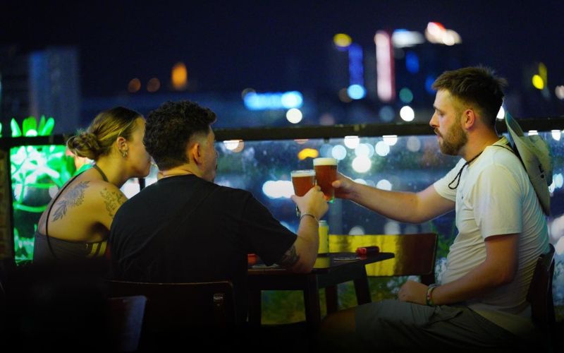 Friends enjoying drinks with live music and city lights in a cozy rooftop setting