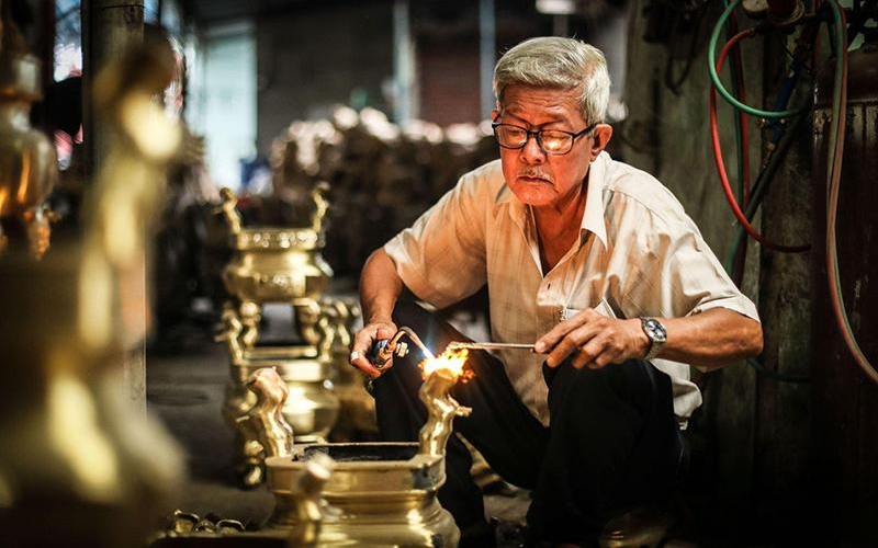 A local artisan shaping bronze at Phuoc Kieu Bronze Casting Village