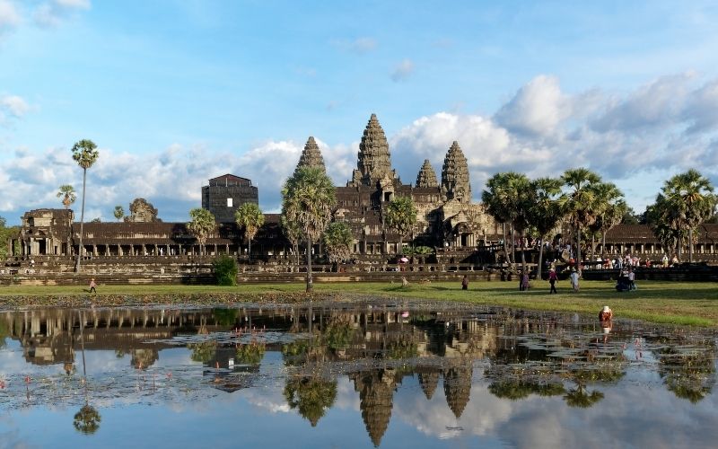 Angkor Wat temple complex in Cambodia with reflection on the water under a partly cloudy sky