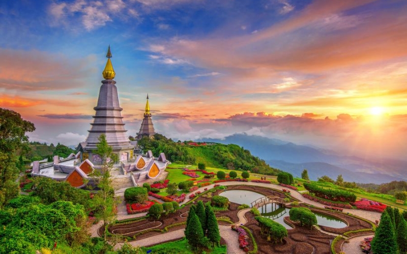 View from the summit of Doi Inthanon in the early morning with clouds rolling over forested mountains.