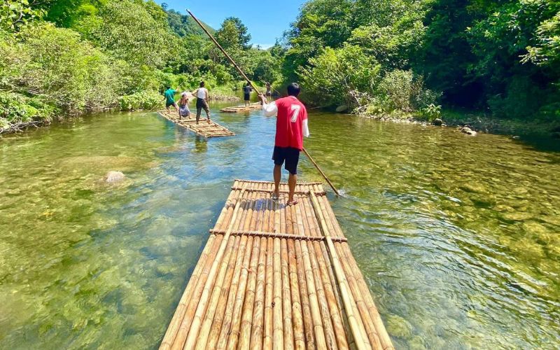 Bamboo rafting adventure on a clear river in Chiang Mai, Northern Thailand, surrounded by lush jungle scenery
