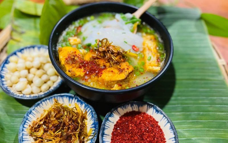Traditional Quang Tri catfish porridge served with herbs, chili, and side dishes on banana leaf