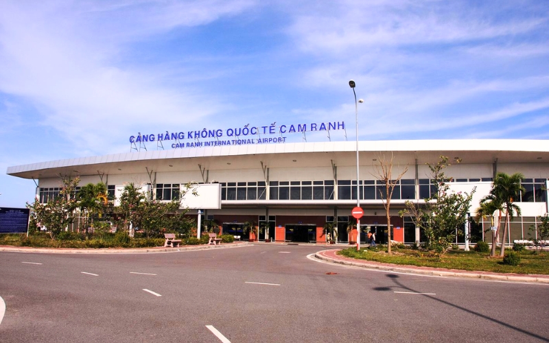 Exterior view of Cam Ranh International Airport terminal building with palm trees and a clear blue sky.