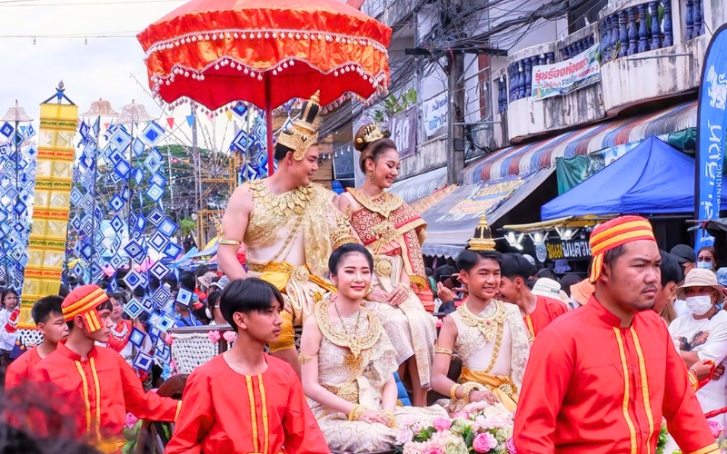 A colorful scene from Phi Ta Khon Festival in Dan Sai, showing performers in traditional Thai royal costumes on decorated floats, symbolizing the return of Prince Vessantara in Buddhist legend, whose homecoming is so joyful that even spirits join the celebration