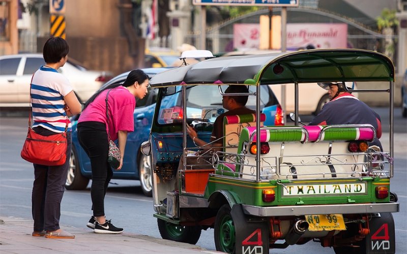 A tuk-tuk driver approaching tourists with a “special deal” offer near a popular Bangkok temple.