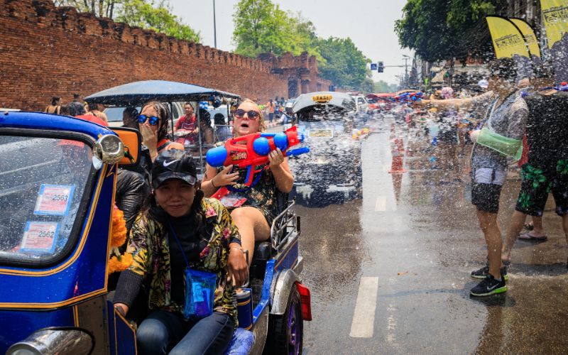 Tourists firing water guns from a tuk-tuk during Songkran Festival on the moat road in Chiang Mai, Thailand