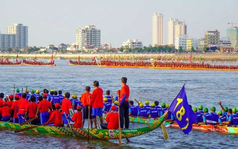 Colorful rowing boats competing in the Bon Om Touk Water Festival in Phnom Penh, Cambodia, with city skyline in the background