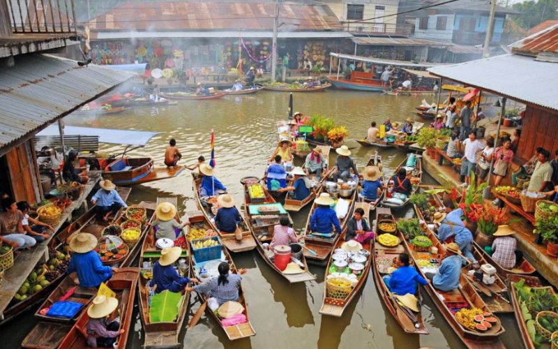 Colorful floating market in Thailand with vendors selling fruits, food, and goods from wooden boats