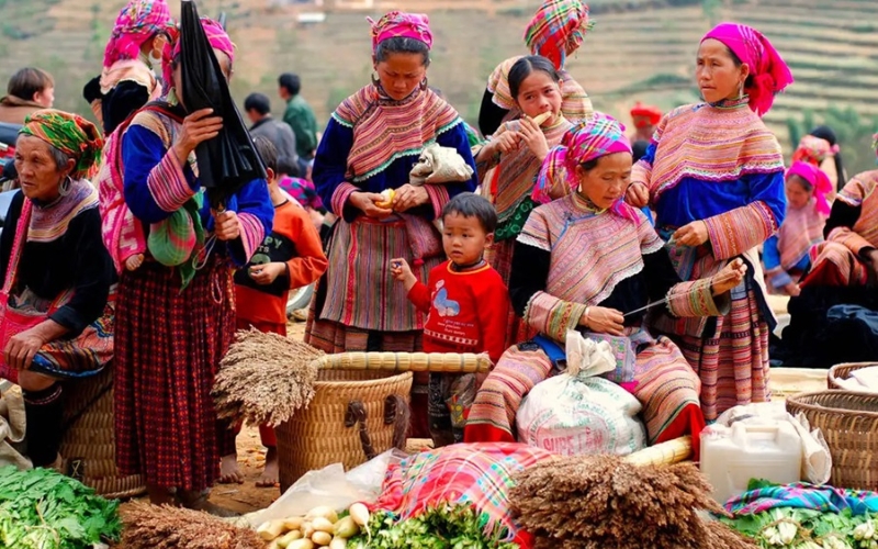 Colorful ethnic Hmong women at a traditional mountain market in Northern Vietnam, selling local produce and handmade goods