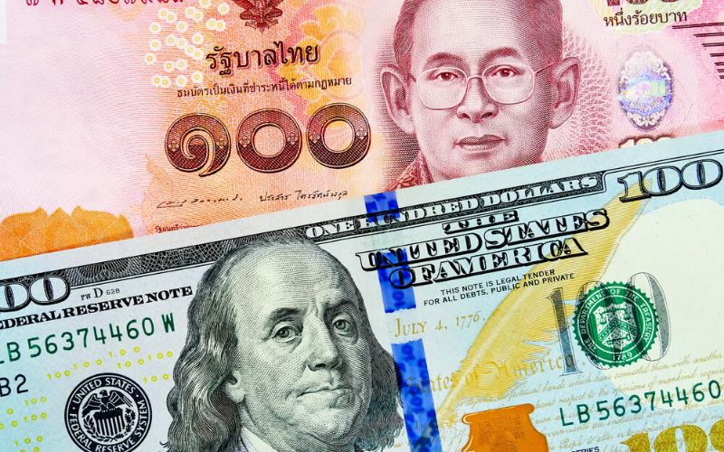 Close-up of Thai 100 baht banknote and U.S. 100 dollar bill side by side, illustrating currency exchange between Thailand and the United States