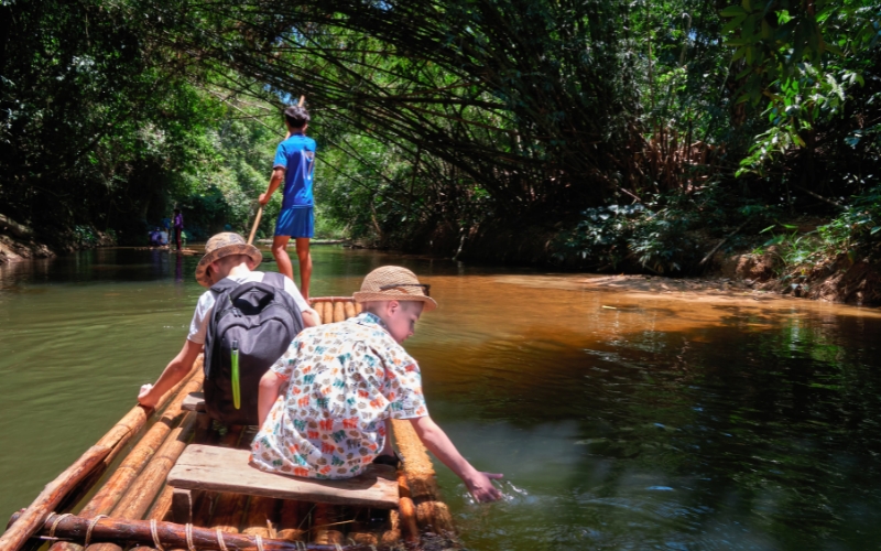 Traveler sitting on a bamboo raft gliding through a green river in Chiang Mai