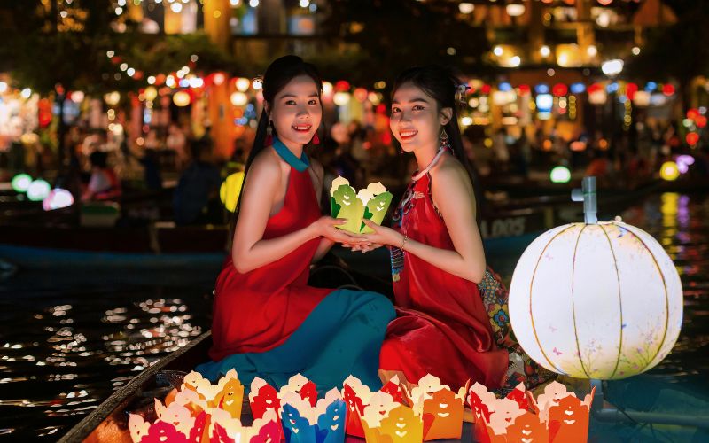 Women floating lantern flowers on Hoai River in Hoi An, a peaceful tradition bringing luck and beauty to the night market scene