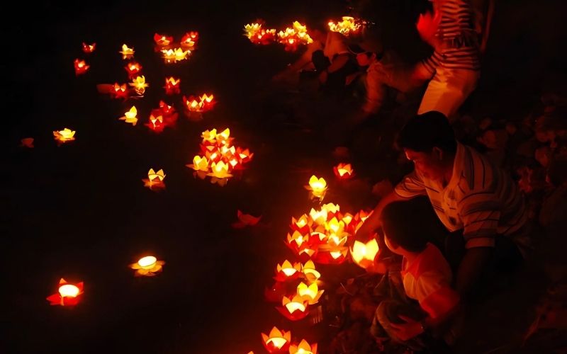 People releasing glowing flower lanterns onto the river during the Lai Heua Fai Festival in Luang Prabang, Laos.