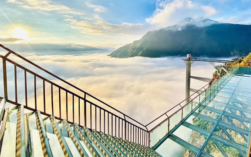 Glass skywalk and stairs overlooking a sea of clouds and mountain peaks in Sapa, offering visitors a thrilling and panoramic view from high above.