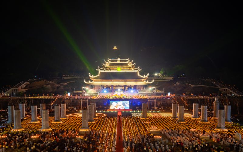 Thousands of Buddhists gathering at night for the Vu Lan Festival (Ghost Festival) in Hanoi, featuring a candle-lit ceremony and illuminated temple architecture.