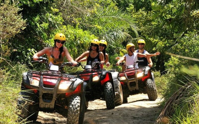 Group of tourists riding ATVs through a tropical jungle trail during an adventure tour in Phuket, Thailand