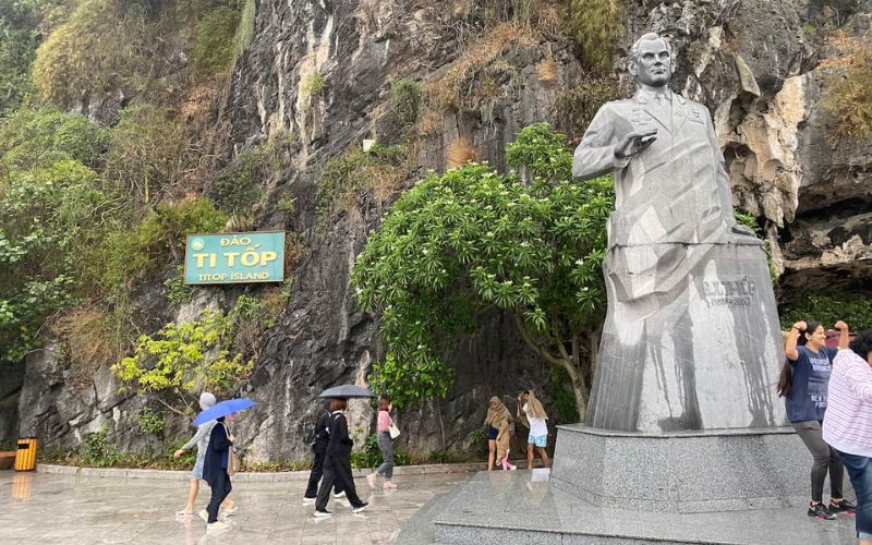 Statue of Gherman Titov at the entrance of Ti Top Island in Ha Long Bay, with visitors arriving before climbing to the viewpoint