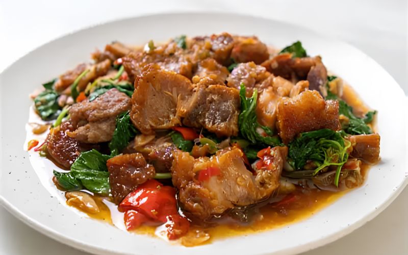 A plate of gaeng hung lay, northern Thai pork curry with tender braised pork belly, chili, and herbs, served on a white plate.