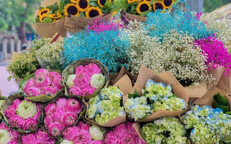 Colorful bouquets of lotus blossoms, sunflowers, and hydrangeas displayed on a street vendor's bicycle during the Hanoi Autumn Festival.
