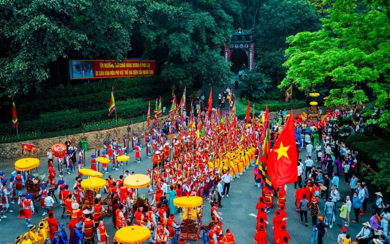 Colorful procession at the Hung Kings Temple Festival in Phu Tho, Vietnam, with participants in traditional costumes carrying flags and ceremonial parasols