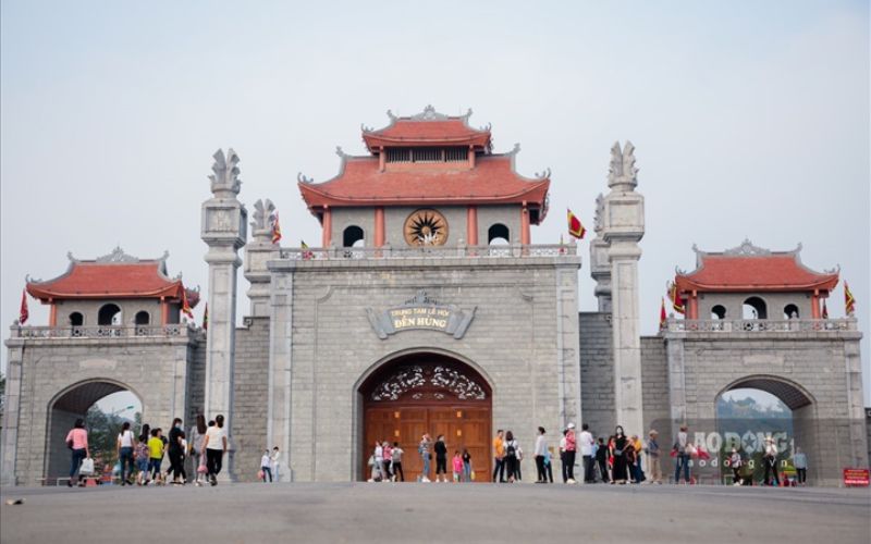 Grand entrance gate of the Hung Kings Temple Complex in Phu Tho, Vietnam, with traditional red-tiled roofs and visitors gathered in front