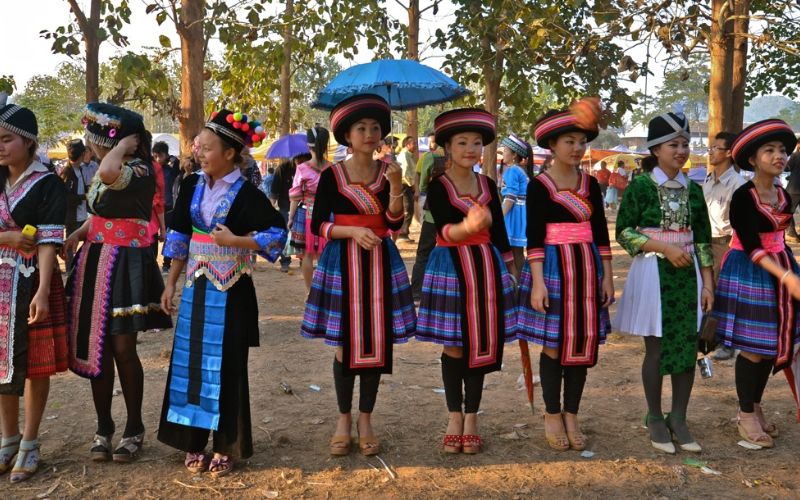 Hmong women in traditional attire celebrating the Hmong New Year outdoors.