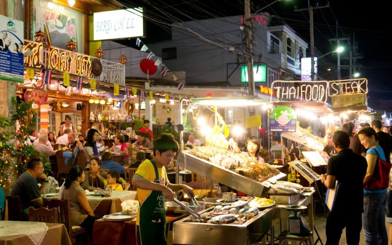 Crowds browsing food stalls at Hua Hin Night Market, vibrant with lights, street food, local vendors, and a lively evening atmosphere