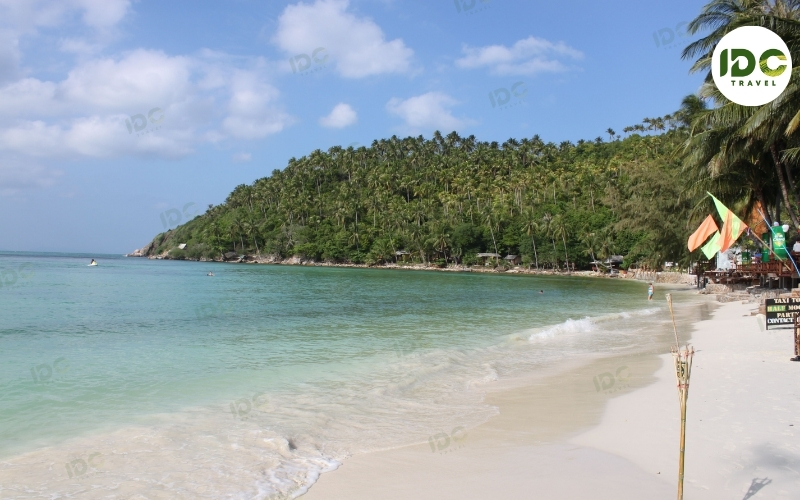 Curved sandy bay backed by coconut palms and green hills at Haad Salad on Koh Phangan, Thailand.