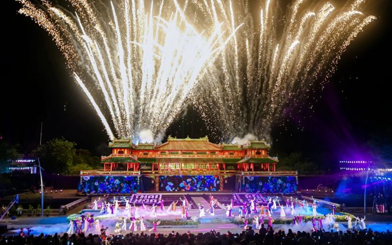 Fireworks lighting up the sky above a grand stage performance at Hue Festival, set in front of the historic imperial palace in Vietnam.