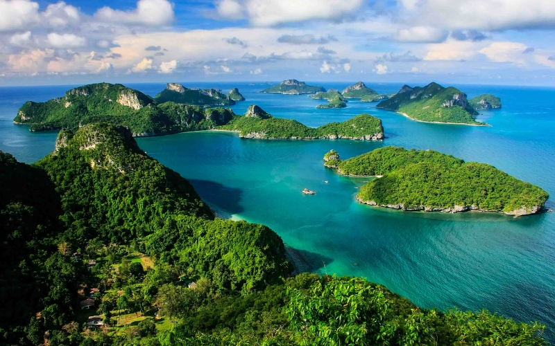 Aerial view of a Thai island surrounded by clear turquoise water and coral reefs.
