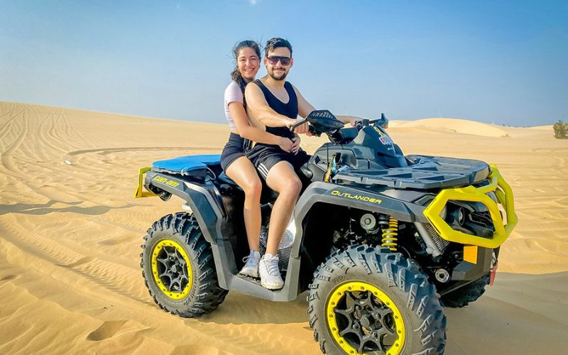 Couple riding an ATV on the sand dunes during a jeep tour in Mũi Né, Vietnam—an exciting desert adventure experience