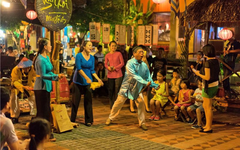 Tourists and locals playing traditional Vietnamese folk games at Hoi An Night Market, enjoying lively cultural street entertainment