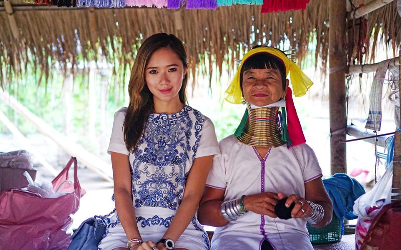 Tourist with Karen long-neck woman in traditional attire at Karen village, Chiang Rai, Northern Thailand