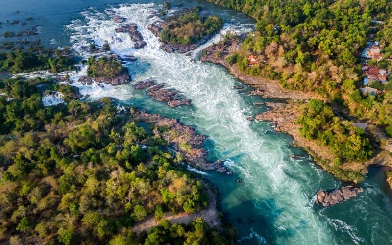 Scenic view of Khone Falls in southern Laos, featuring powerful cascading waterfalls surrounded by lush greenery