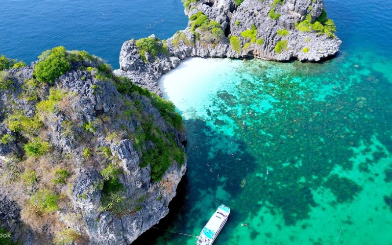 Wide sandy beach in Koh Lanta, Thailand, with turquoise waters and palm trees, ideal for relaxation and swimming.