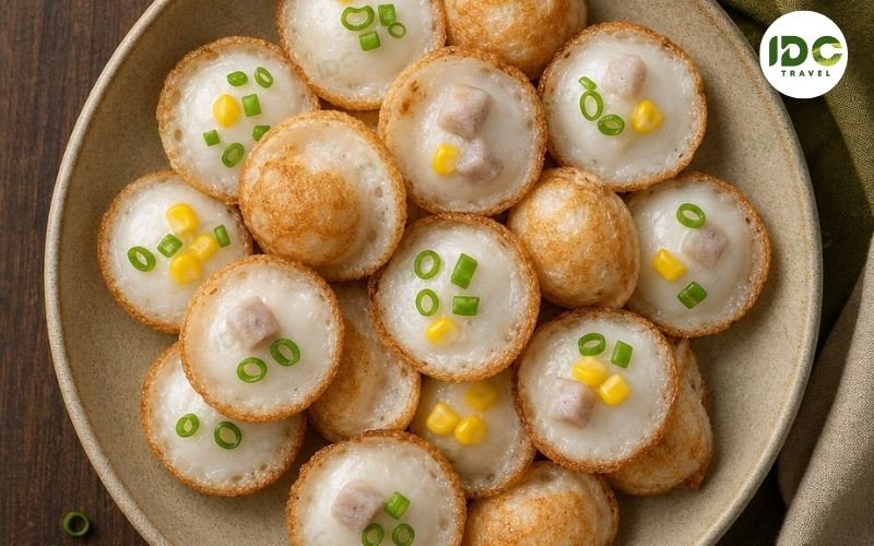 A plate of khanom krok, Thai coconut rice pancakes topped with corn and scallions.