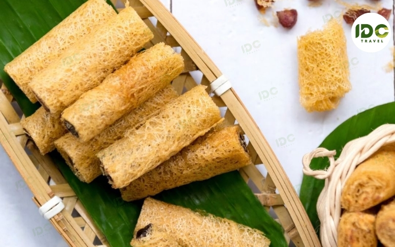 Khanom la, Thai fine-thread rice flour sweet rolled into crispy golden rolls, served on a banana leaf.