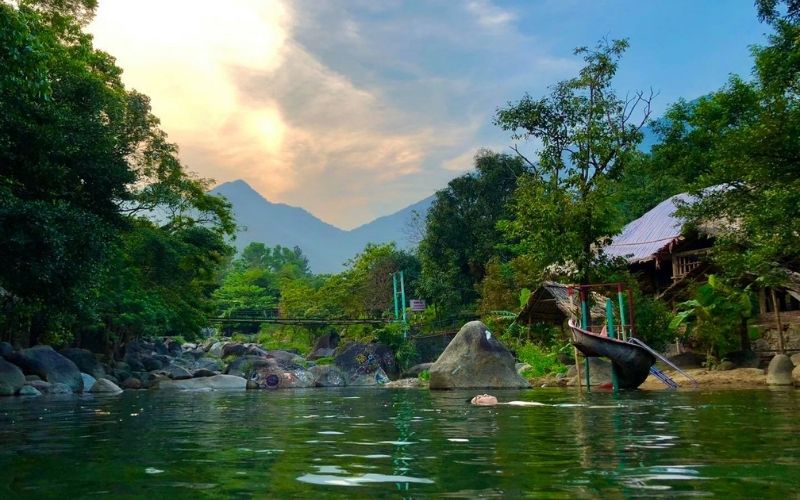 Luong Stream in Da Nang: tranquil green waters, lush forest, and rustic huts create a peaceful natural retreat