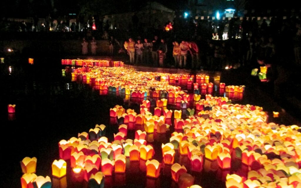Floating lanterns reflecting on the Thu Bon River in Hoi An, as families and travelers gather to celebrate the Mid-autumn Festival.