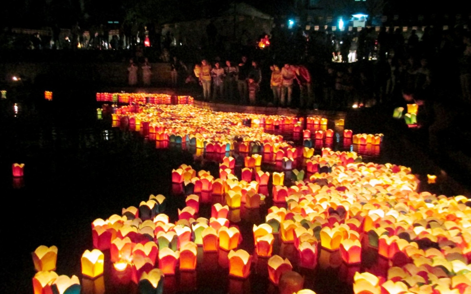 Floating lanterns reflecting on the Thu Bon River in Hoi An, as families and travelers gather to celebrate the Mid-autumn Festival.