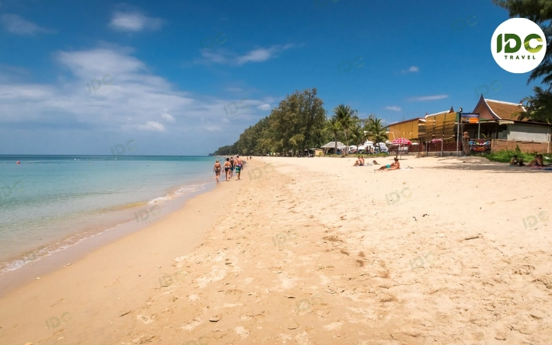 Wide golden sand and gentle waves at Long Beach on Koh Lanta, Thailand, with beach bars among the trees.