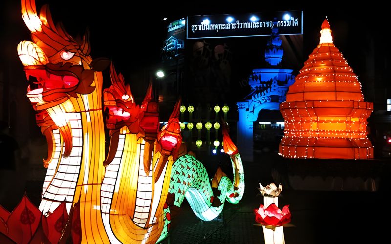 Colorful lantern parade during Yi Peng Festival in Chiang Mai featuring illuminated dragon and temple-shaped lanterns at night