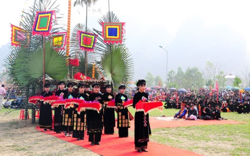 People in traditional ethnic costumes celebrating the Long Tong Festival in Northern Vietnam, with colorful flags, music, and lively performances marking the start of the farming season.