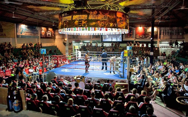 Packed crowd cheering as two Muay Thai fighters face off in the ring at Bangla Boxing Stadium in Patong, Phuket.