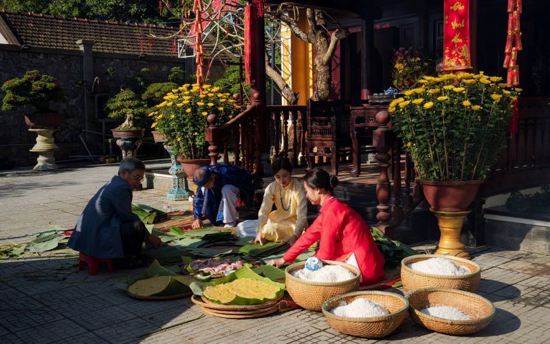 Vietnamese family gathering to make Banh Chung and Banh Tet, traditional sticky rice cakes for Tet holiday.