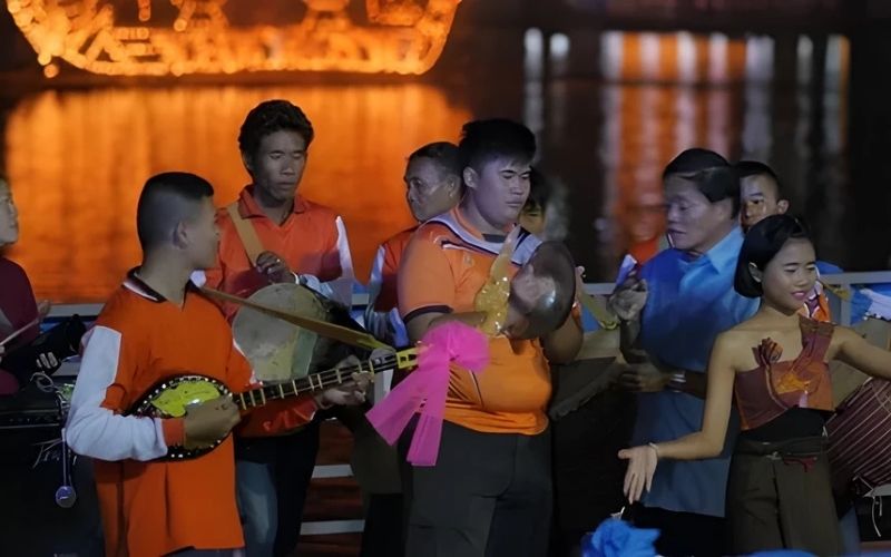 Traditional music performance during the Lai Heua Fai Festival in Luang Prabang, Laos, with musicians playing instruments by the riverside lantern display.