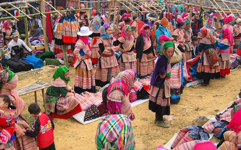 Meo Vac Market in Ha Giang, Vietnam, bustling with ethnic minority traders in colorful traditional clothing, selling fresh produce, livestock, and handmade goods